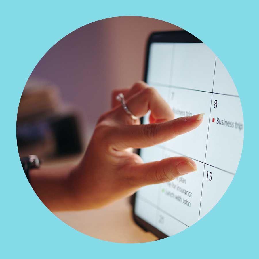 Eine Hand zoomt gerade mit der Bewegung von Daumen und Zeigefinger an einen digitalen Kalender ran.