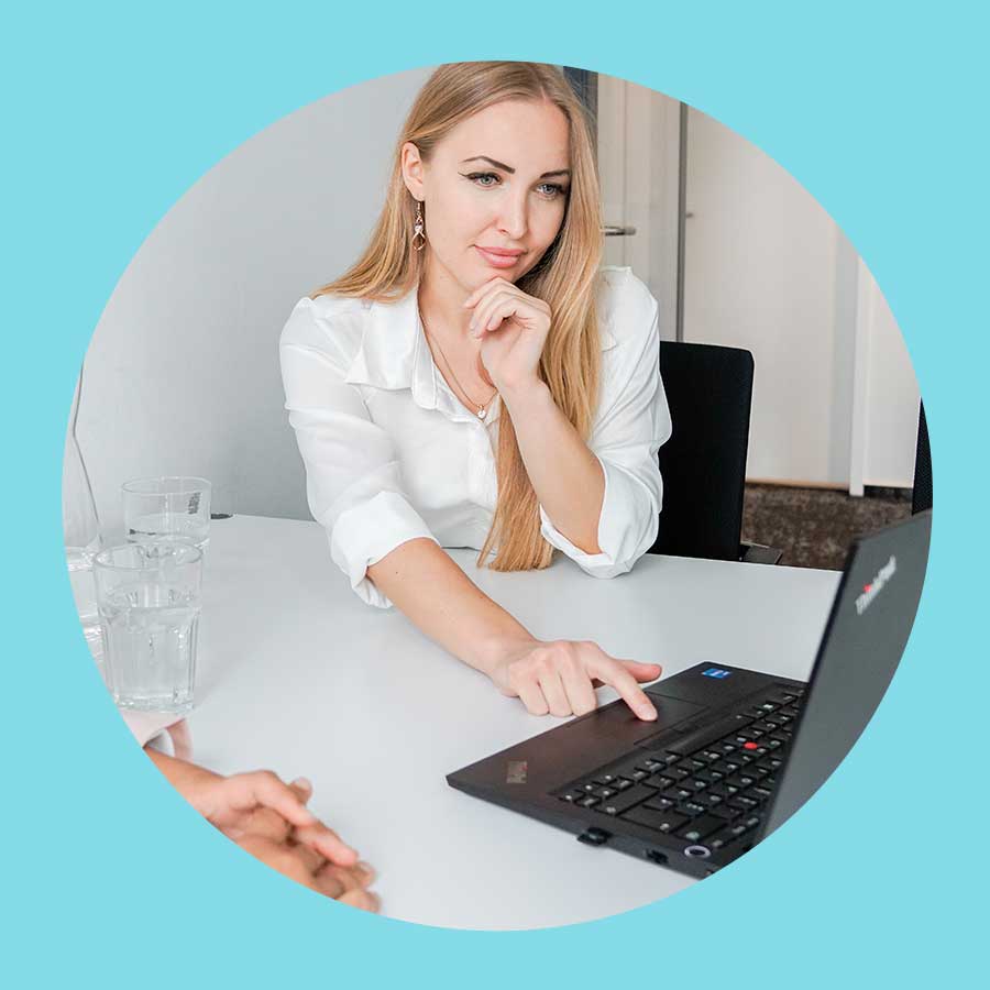Celina Sever, Recruiterin und zuständig für Jobs im Bereich Photovoltaik, schaut interessiert mit der Hand am Kinn und dem Ellbogen auf dem Tisch auf ein Laptop. Man sieht eine zweite Person im Anschnitt aber nicht viel.